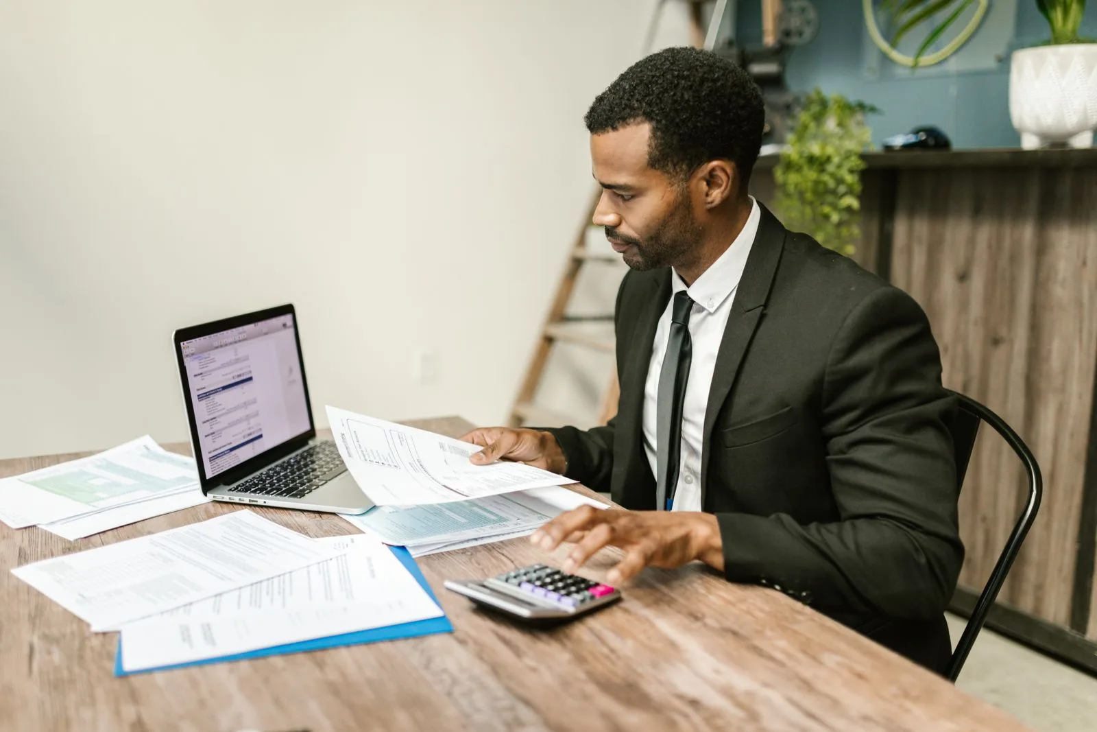 Fixed income professional working through bond documents with a calculator and laptop