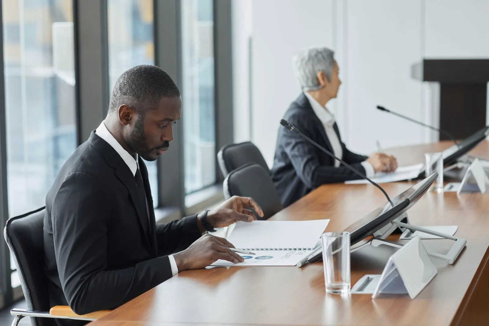 Research analyst in a suit and tie reviewing reports at a boardroom table